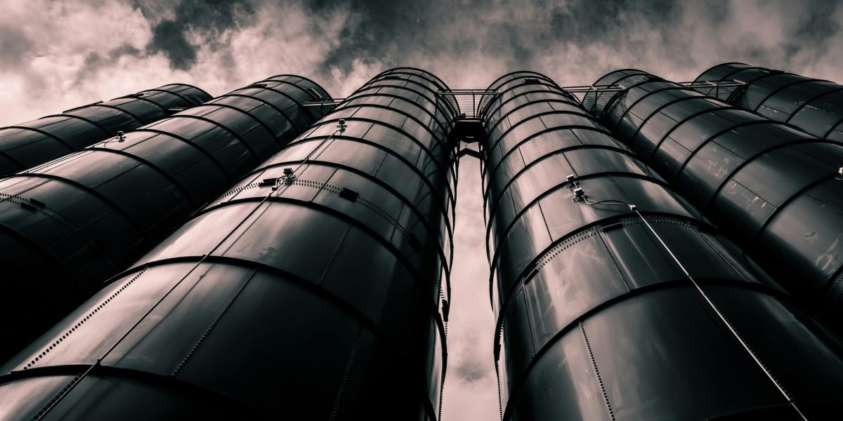 Low angle view of industrial silos with a dramatic cloudy sky in the background, emphasizing modern industry.